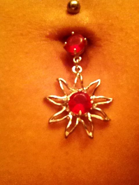 a woman's belly is adorned with a red and silver jeweled navel ring