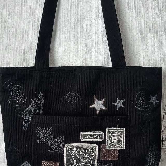 a black tote bag hanging on a wall with stars and other things in it