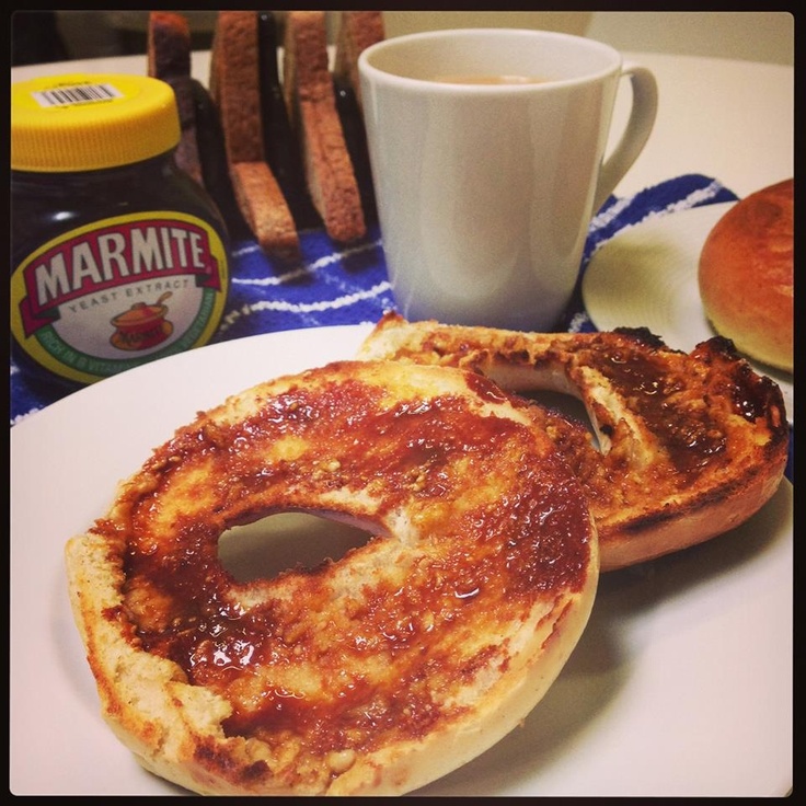 two bagels sitting on top of a white plate next to a cup of coffee