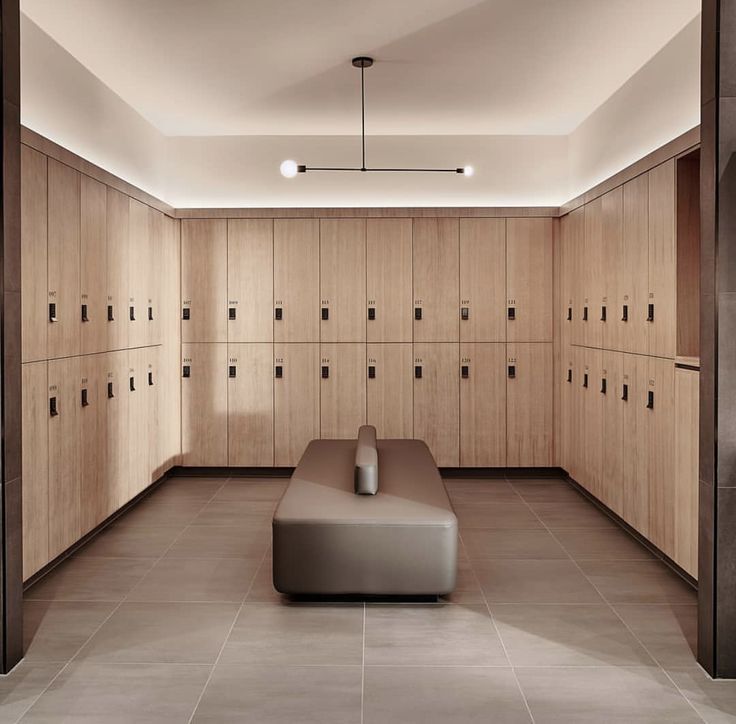 an empty room with wooden lockers on the walls and benches in the middle,