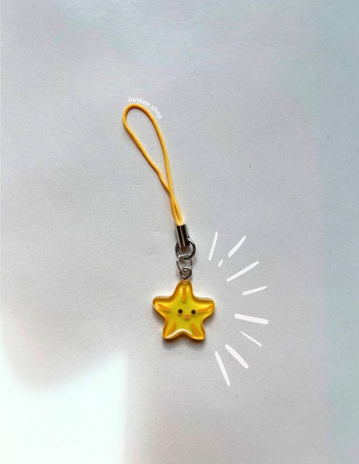 a yellow star shaped keychain hanging from a clip on a white table top