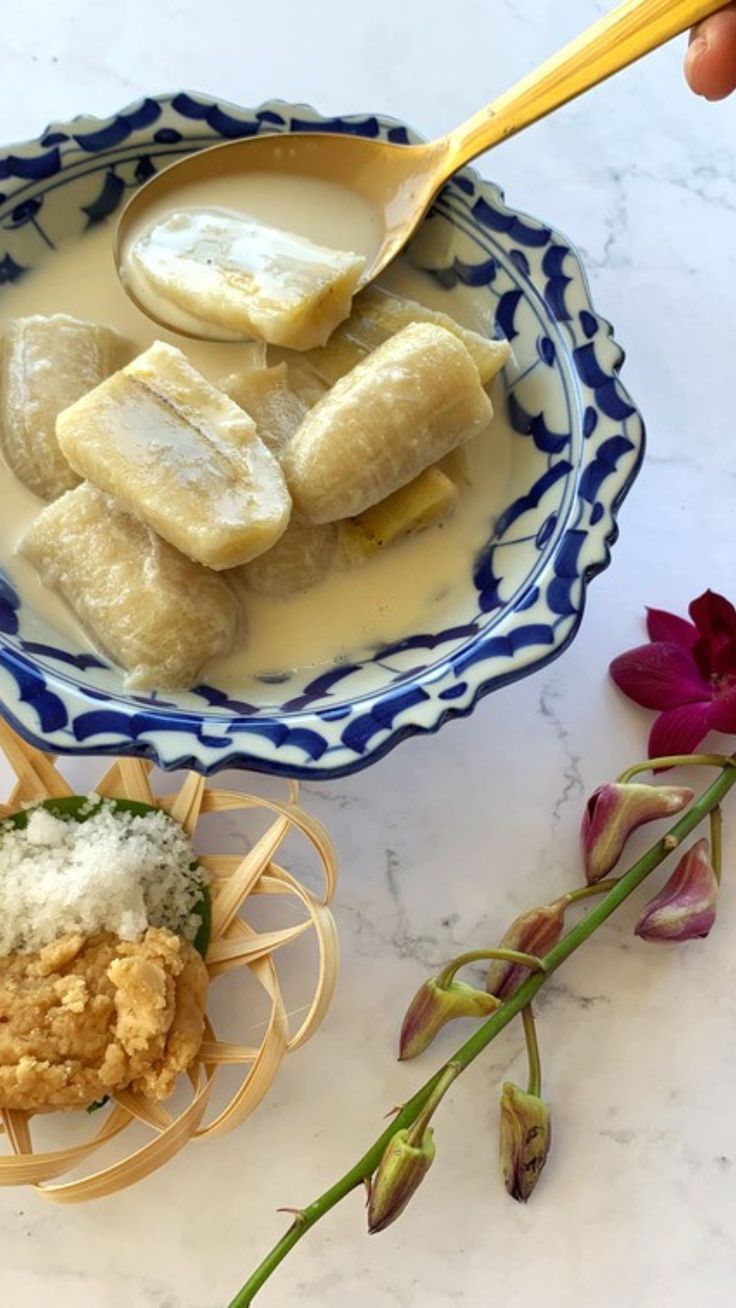 bananas and other food items in a bowl on a table next to some purple flowers