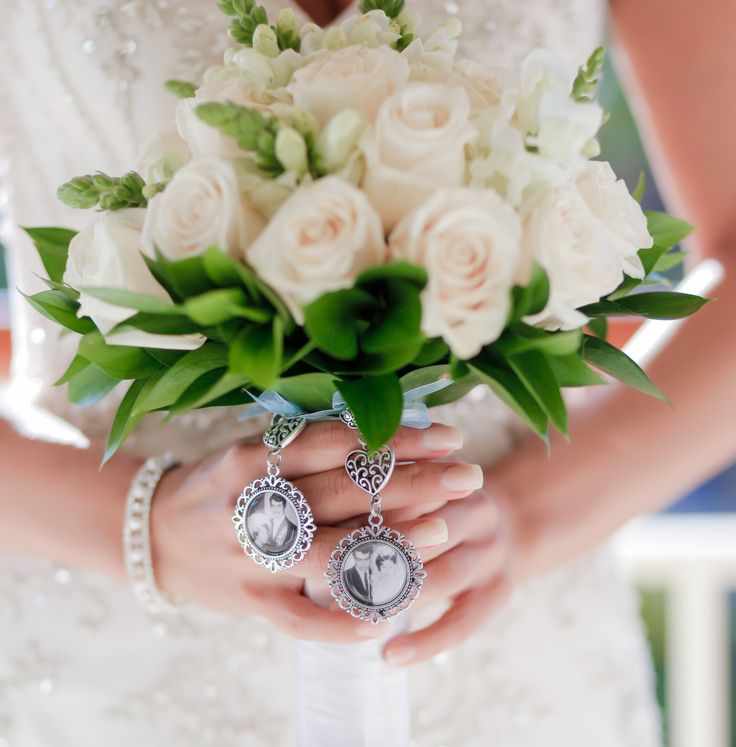 a bride holding a bouquet with white roses and brooches on her wedding day