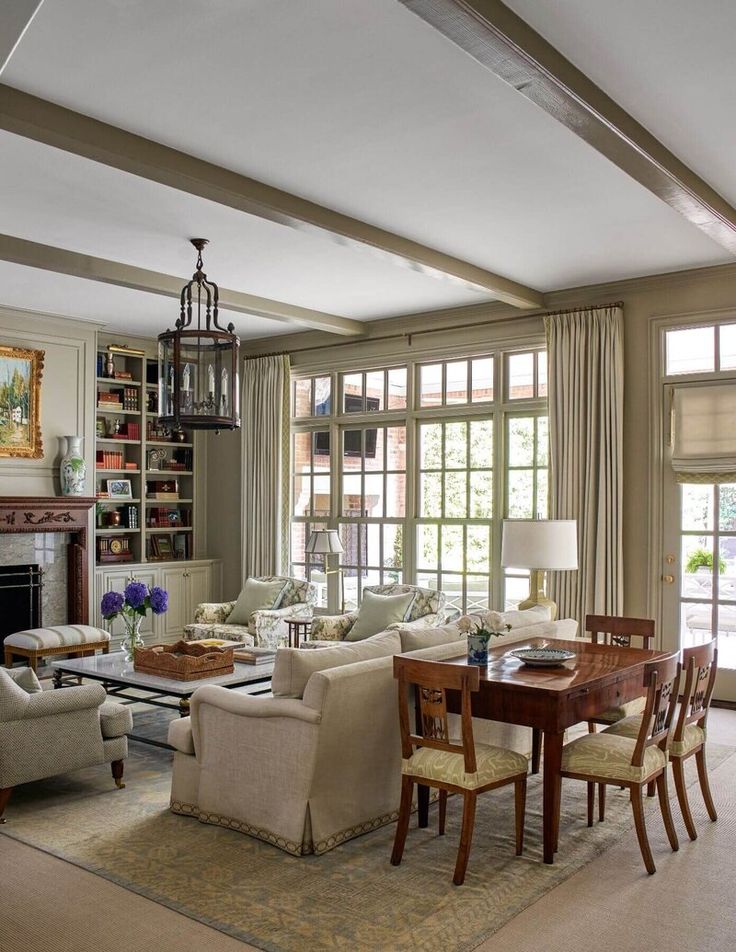 a living room filled with furniture and a fire place in front of a window covered in bookshelves