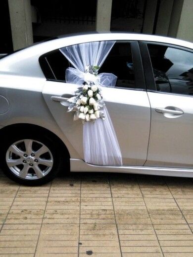 a silver car is decorated with white flowers