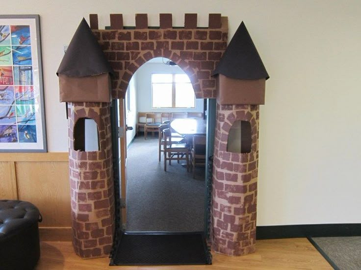 a castle made out of cardboard sitting on top of a hard wood floor next to a window