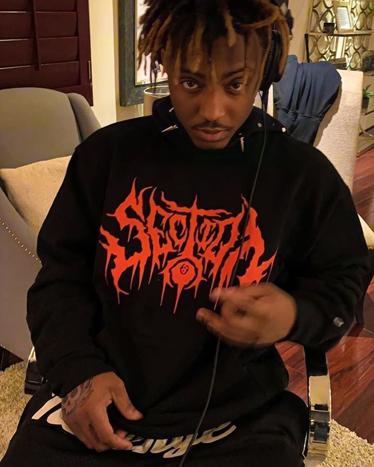 a young man with dreadlocks sitting on a couch wearing a black sweatshirt and headphones