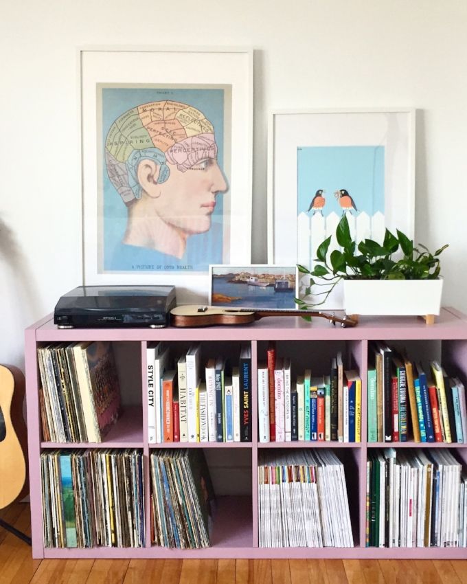 a pink bookcase with various records on it