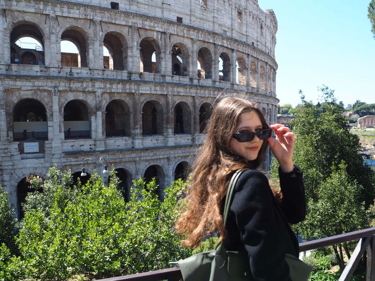 a woman is standing in front of the colossion