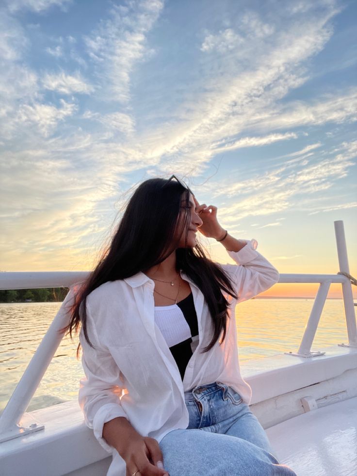 a woman sitting on the back of a boat drinking from a glass in her hand