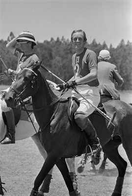 black and white photograph of two men riding horses with people on horseback behind them in the background