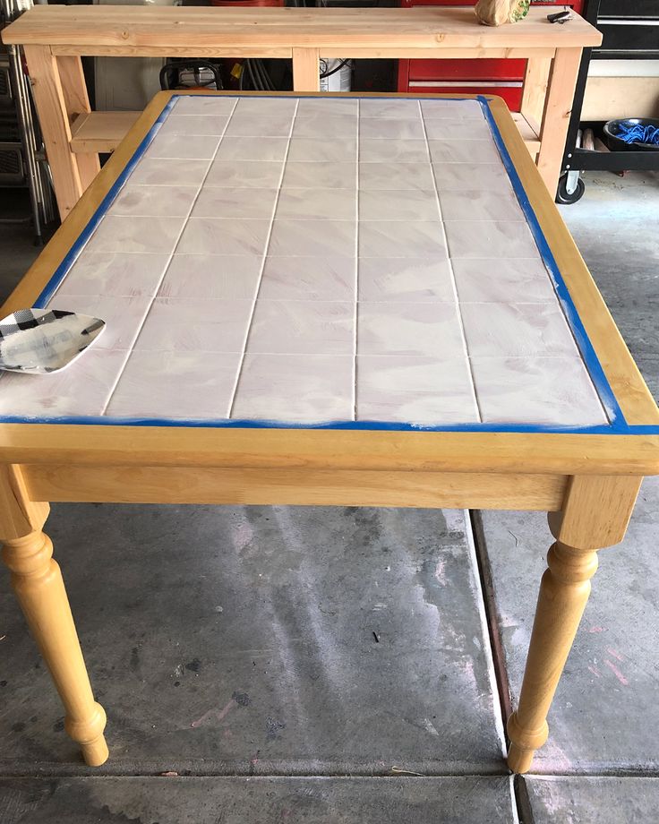 a wooden table with some paint on it and a tool resting on the top one