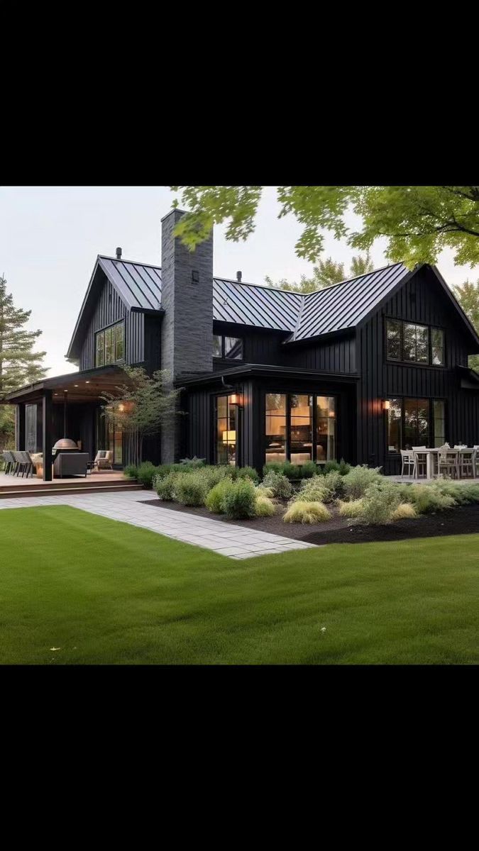 a large black house sitting on top of a lush green field