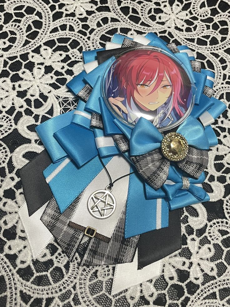 an anime brooch is laying on a lace doily with blue and black ribbons