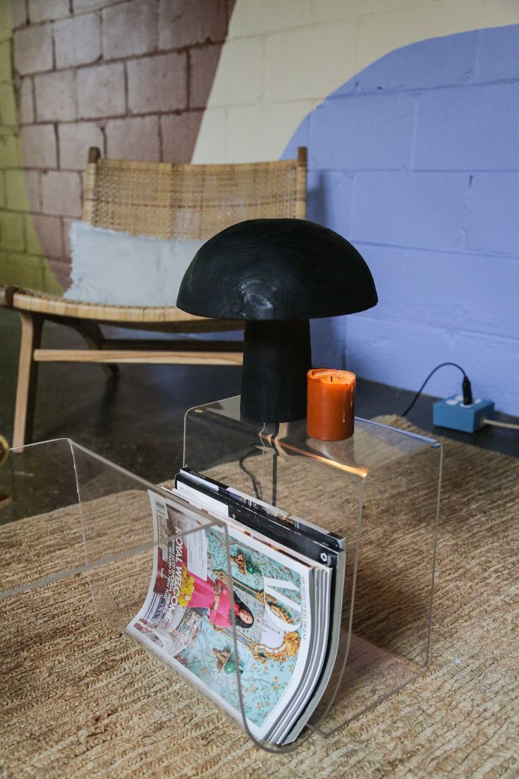 a magazine holder sitting on top of a wooden table next to a chair and wall