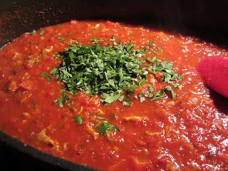 a pot filled with red sauce and garnished with parsley