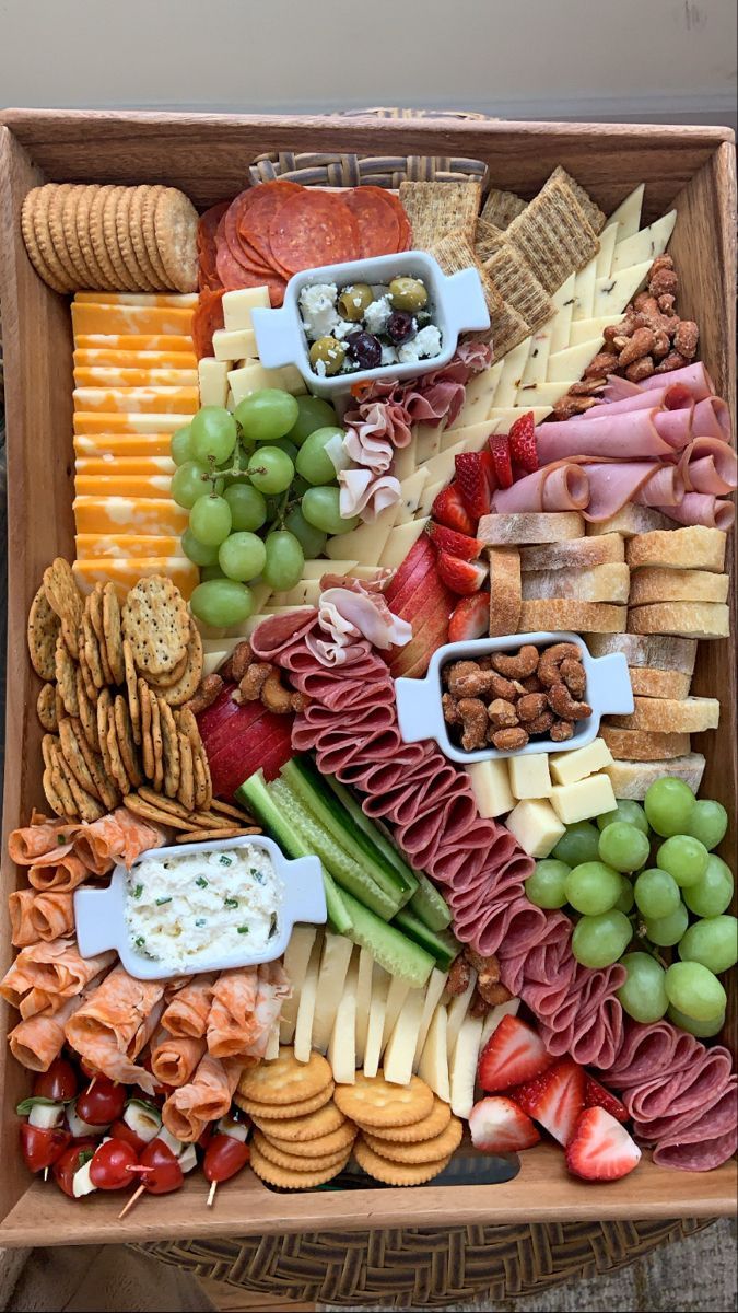 a wooden box filled with lots of different types of cheeses and crackers on top of each other