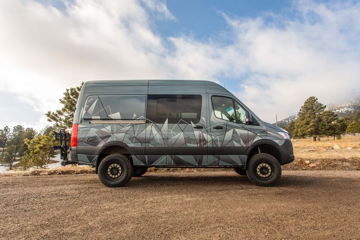 a van parked on the side of a dirt road with trees in the back ground