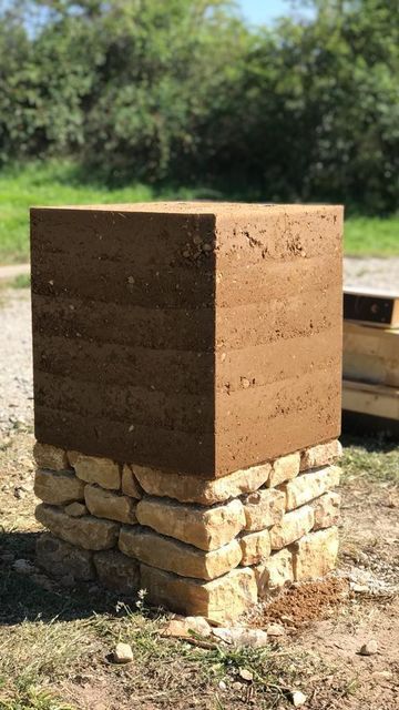 a large brick structure sitting on top of a dirt field next to a wooden box