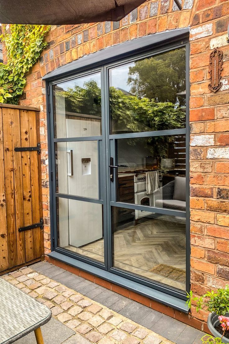 an open sliding glass door in front of a brick building