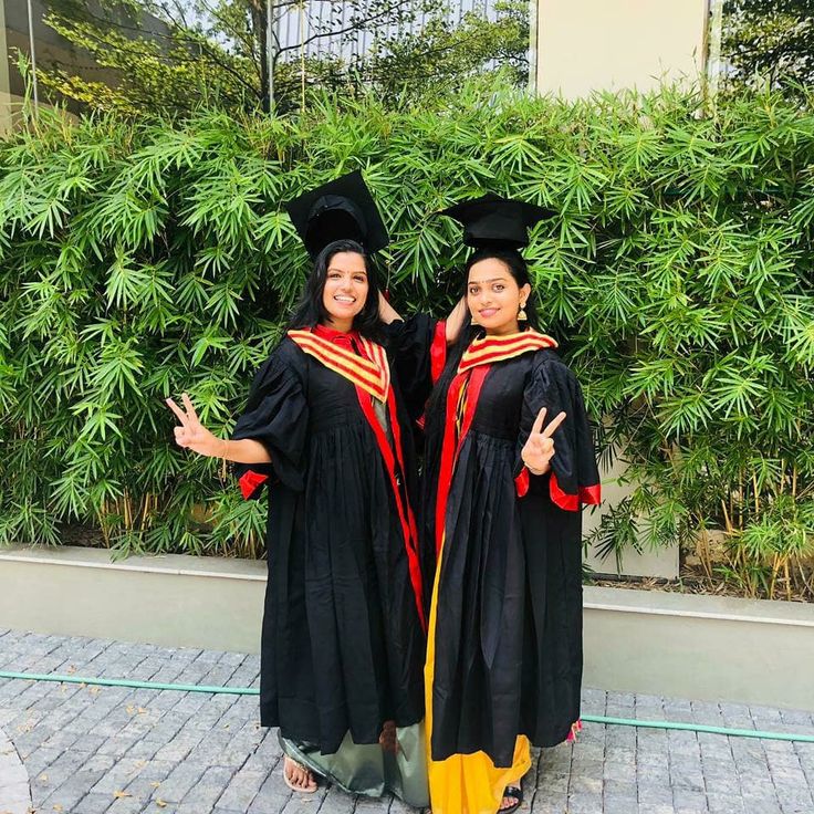 two women in graduation gowns standing next to each other