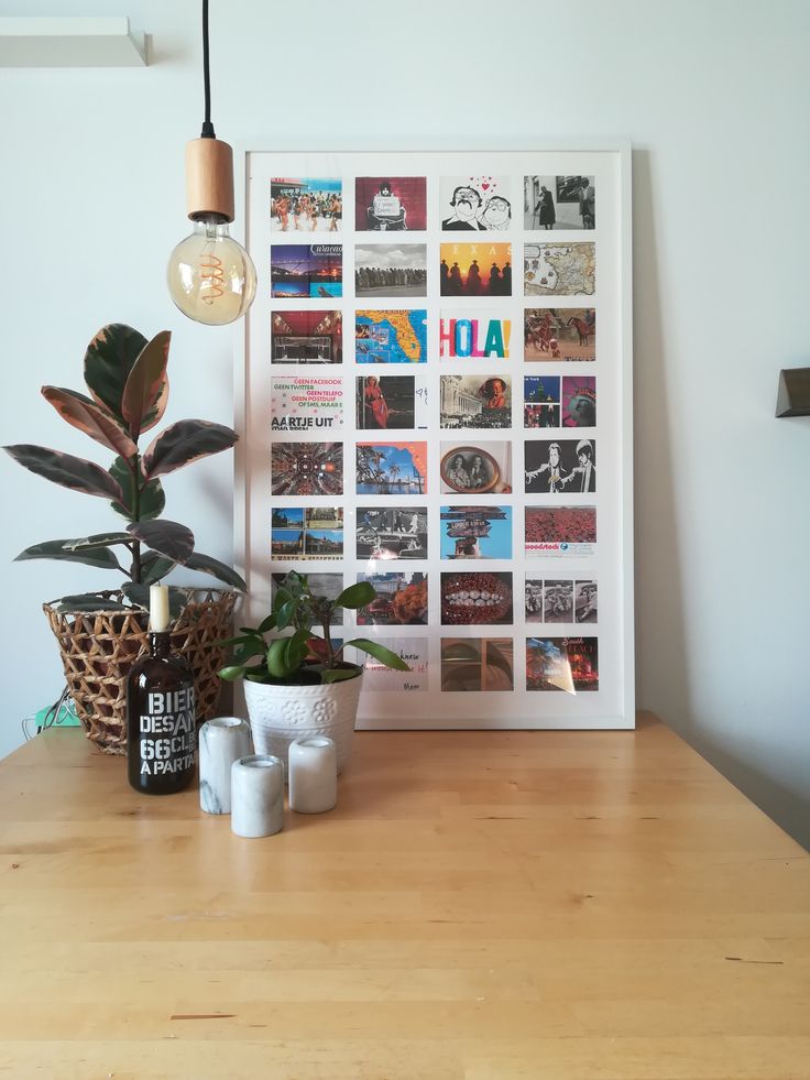 a wooden table topped with potted plants next to a white framed poster on the wall