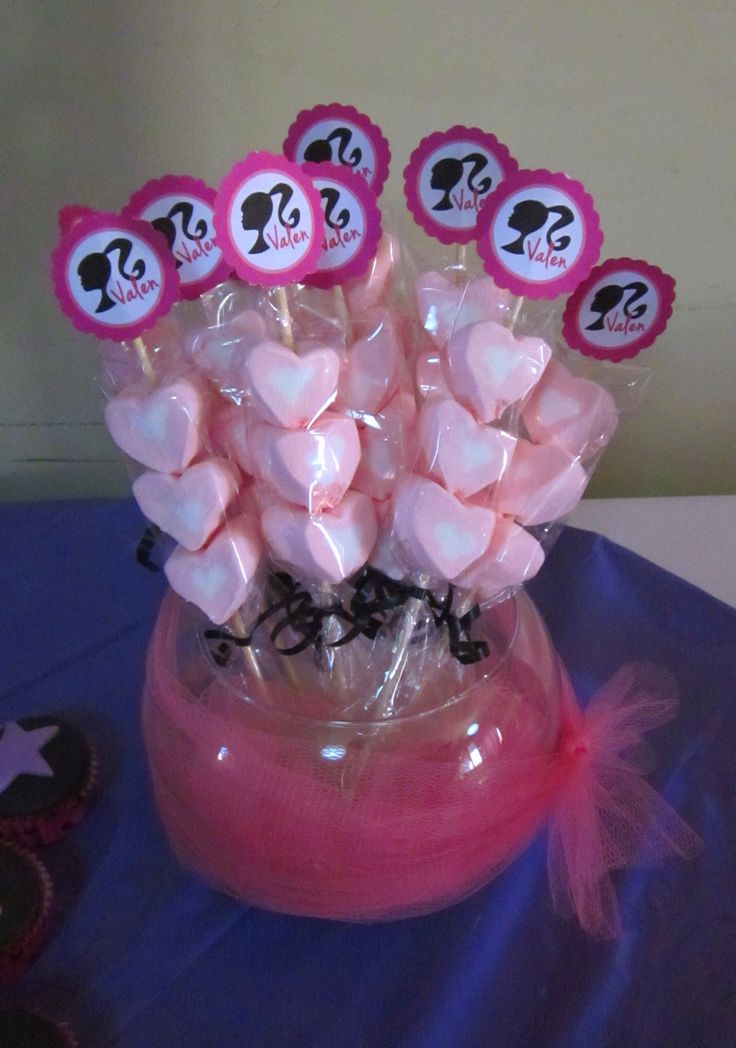 a vase filled with lots of pink candy hearts on top of a blue table cloth