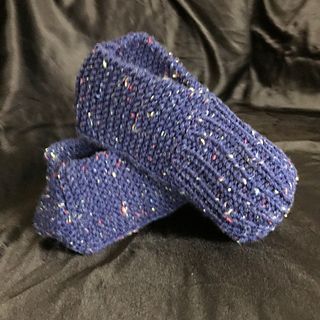 a pair of blue knitted slippers with skulls on the side and purple background