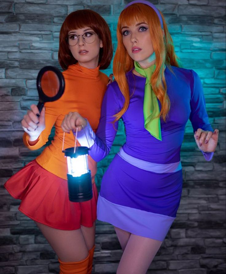 two women dressed up in costumes and holding magnifying glass with light shining on them