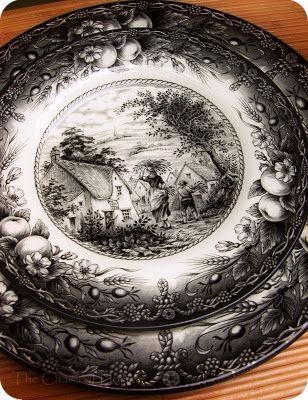 an antique black and white plate sitting on top of a wooden table