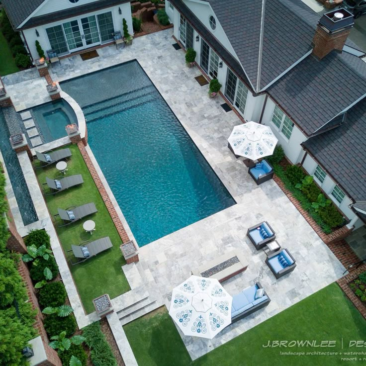 an aerial view of a pool with lounge chairs and umbrellas in the foreground