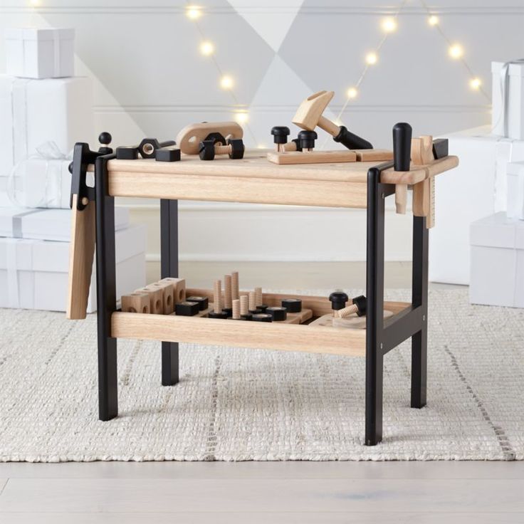 a wooden workbench with tools on it in front of a white wall and string lights