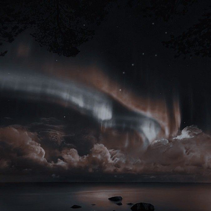 an aurora bore is seen in the night sky above some clouds and water with rocks on the ground