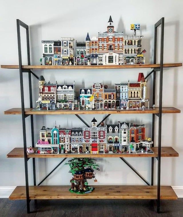 a shelf filled with lots of toy houses on top of wooden shelves next to a wall