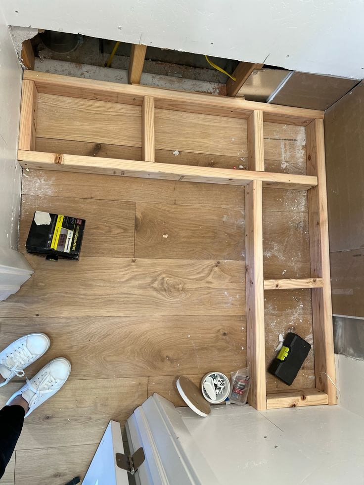 an overhead view of a room with wood flooring and construction materials on the ground