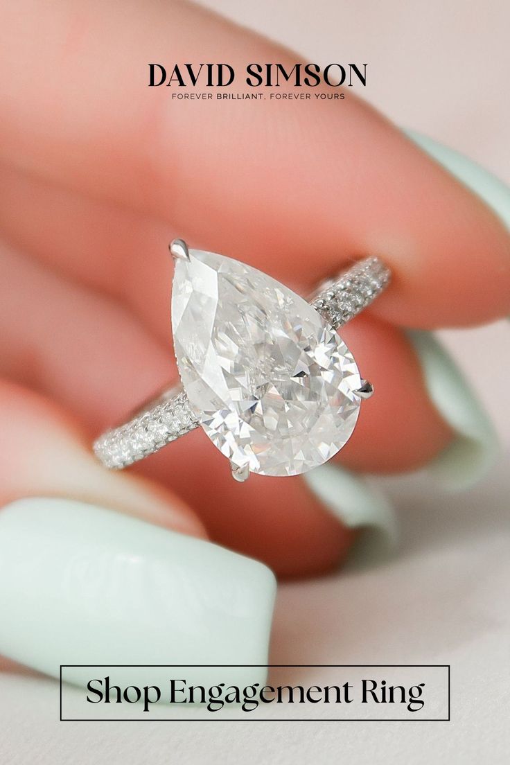 a close up of a person's hand holding an engagement ring