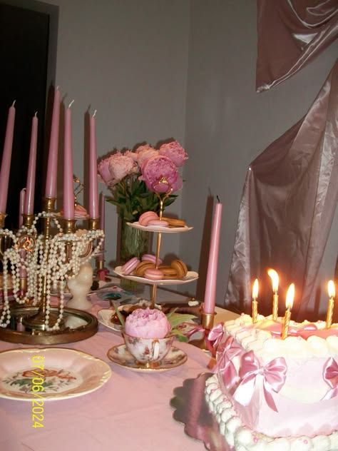 a table topped with a cake covered in pink frosting and lots of lit candles