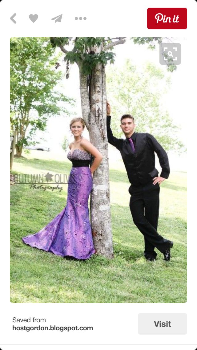 a man and woman standing next to a tree