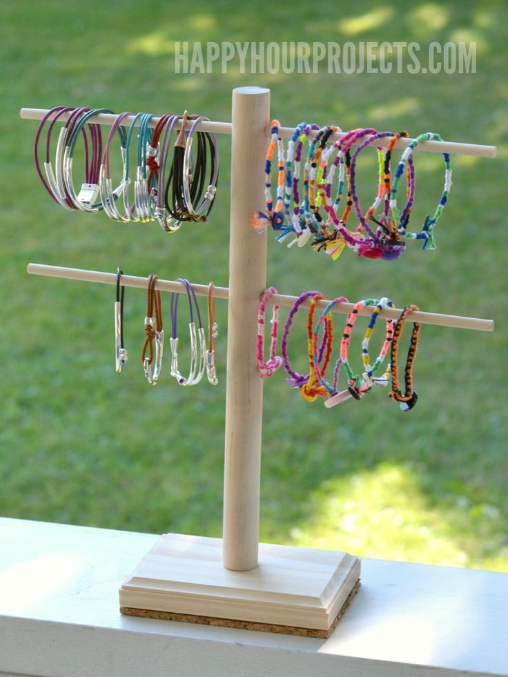 a wooden stand holding several pairs of bracelets on it's sides, with grass in the background