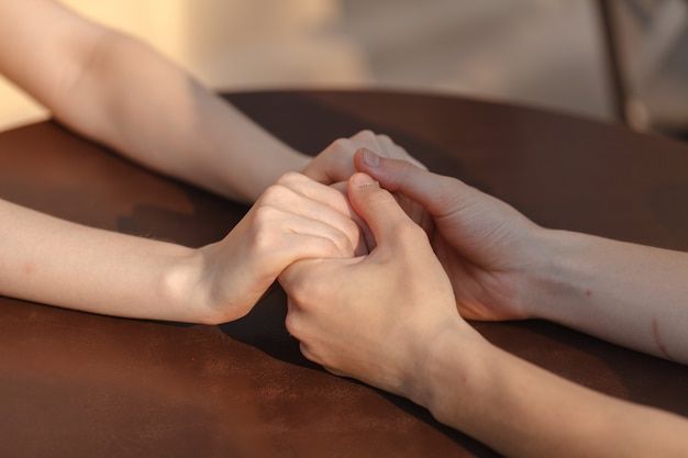 two people holding hands on top of a table