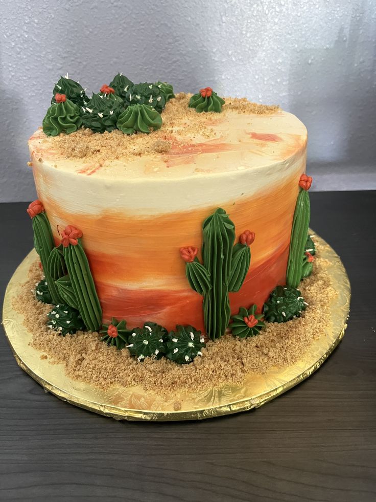 a desert themed cake with cactus decorations on the top and bottom layer, sitting on a wooden table