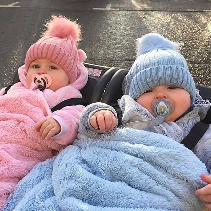 two babies in strollers one is wearing a pacifier and the other has a blanket