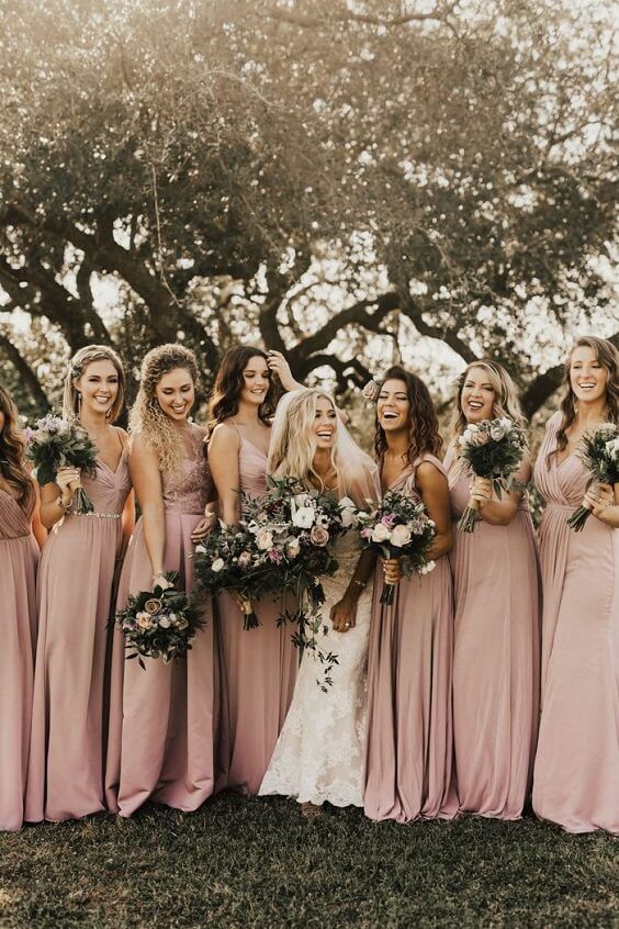 a group of women standing next to each other in front of a tree with flowers