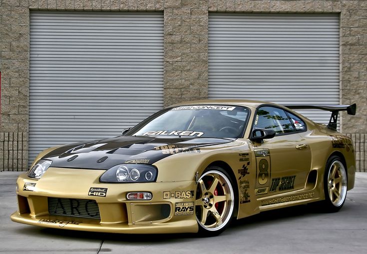 a gold sports car parked in front of a garage door