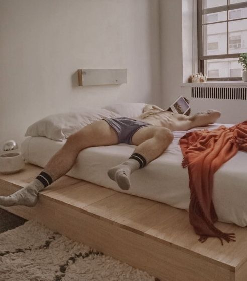 a man laying on top of a bed next to a window