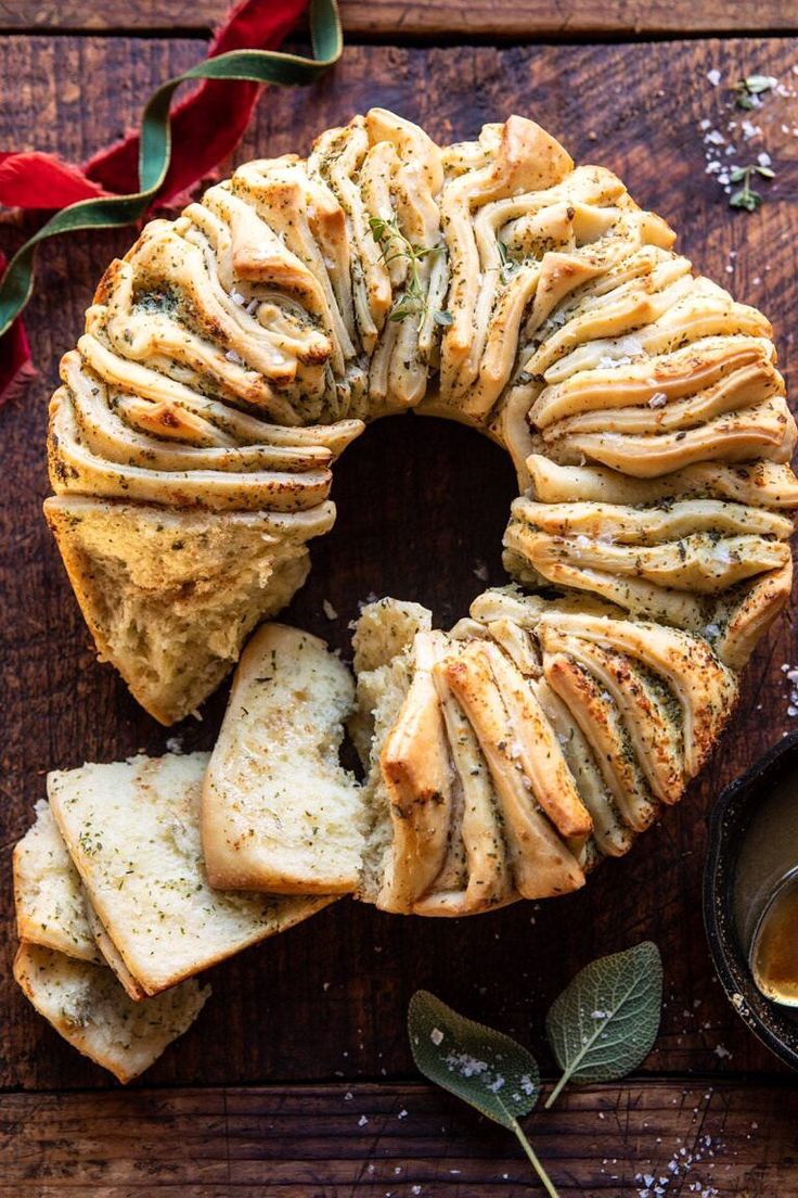 a sliced loaf of bread on top of a wooden table next to some dipping sauce