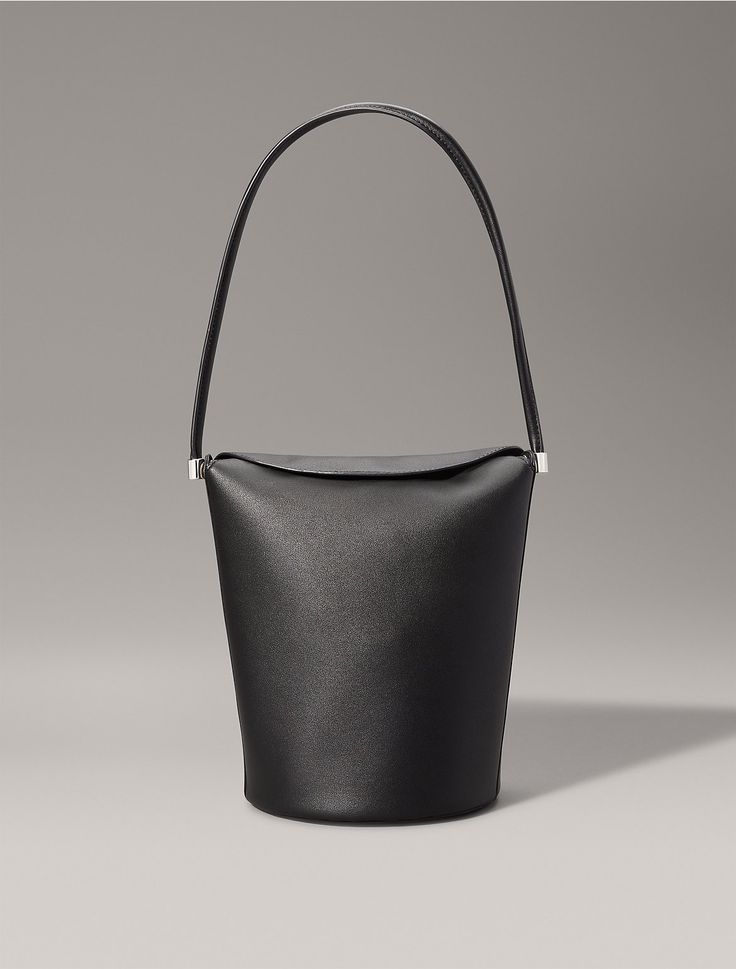 Crafted from 100% faux leather, this shoulder bag features solid, minimal styling. Designed with a top flap closure and detailed with an embossed CK monogram logo at the side. A simple silhouette, this bag is perfect for holding essentials on your evening out.  Material: 100% Polyurethane. Chic Leather Bucket Bag With Magnetic Closure, Modern Calvin Klein Business Bags, Calvin Klein Leather Shoulder Bag With Adjustable Strap, Daily Use Bucket Bag With Magnetic Closure, Leather Crossbody Bucket Bag With Magnetic Closure, Modern Bucket Shoulder Bag With Detachable Strap, Modern Shoulder Bag With Detachable Strap, Bucket Shape, Modern Bucket Shape Shoulder Bag With Detachable Strap, Modern Bucket-shape Shoulder Bag With Detachable Strap