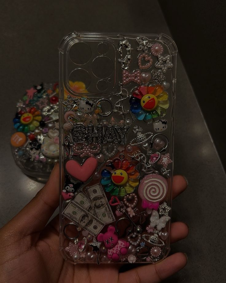 someone is holding up their phone case with many charms on it