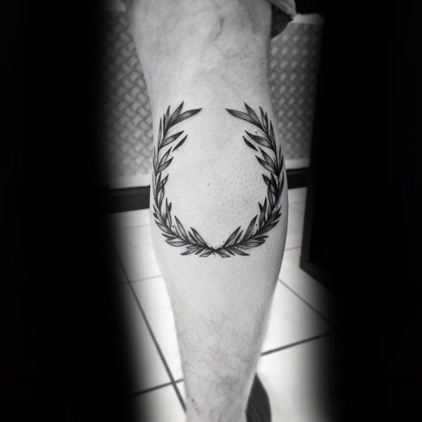 a black and white photo of a man's leg with a wreath tattoo on it