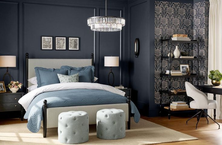 a bedroom with dark blue walls and white bedding, two stools in front of the bed